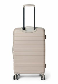 Valise rigide beige clair avec des rainures horizontales, poignée relevable et quatre roues pour la mobilité. Surface texturée pour une meilleure prise en main.