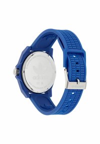 Sinine kummirihmaga kell, millel on ümmargune roostevabast terasest tagakülg. Omab tekstureeritud rihma ja hõbedast sanga, tagaküljel on Adidas logo.