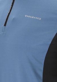 Helles blaues Sportshirt mit schwarzen Seitenpanelen, Reißverschlusskragen und weißem "ENDURANCE"-Logo auf der Brust. Glatte Textur, Sportbekleidungsdesign.