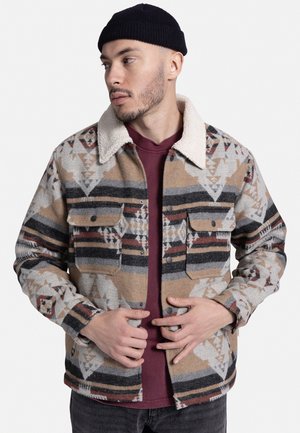 Wool blend shirt jacket with a light fleece collar. Features earthy tones, geometric patterns, and front chest pockets. Black buttons.