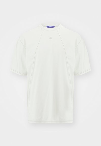 Világos színű, rövid ujjú póló, puha anyagból, kerek nyakkivágással, raglán ujjakkal és diszkrét logóval az elején.