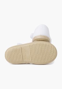 White espadrille with a woven jute sole, featuring a textured rubber bottom and light padding. Small fabric accent near the heel.