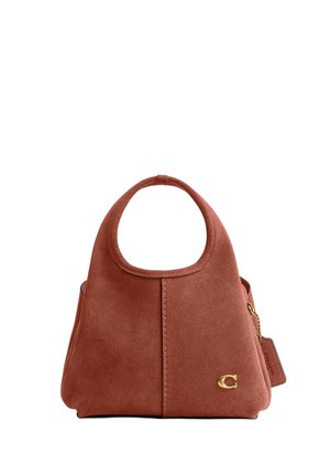 Sac à main en daim couleur rouille avec une poignée ronde découpée, logo "C" doré, et étiquette en cuir attachée avec une chaîne sur le côté.