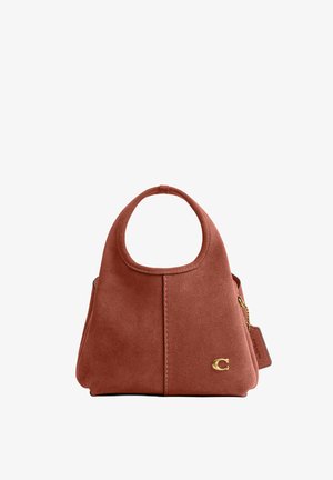 Rđa smeđa torbica od brušene kože s okruglom ručkom izrezanom u obliku otvora, zlatnim logotipom "C" i priloženom kožnom oznakom na lancu sa strane.