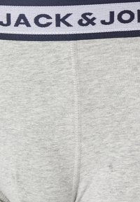 Boxeri gri dintr-un material texturat, cu o talie lată albă pe care este inscriptionat cu litere bleu marin "JACK & JONES". CusăturiNetede pe margini.
