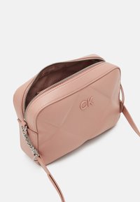 Borsa a mano in ecopelle rosa con design geometricamente trapuntato, dotata di accessori in metallo argentato e chiusura con zip. Presenta un logo impresso sulla parte anteriore.