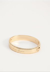 Armband van metaal met goudkleurige coating, geëtst met "Lauren Ralph Lauren"-script en met kralenranden, op een effen witte achtergrond.