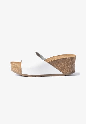 Witte slip-on sleehak sandaal met een textuurachtige kurken plateauzool en open teen, zichtbaar vanaf de zijkant op een witte achtergrond.