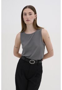 Top gri cu dungi, fără mâneci, cu decolteu rotund, asortat cu pantaloni negri cu talie înaltă și o curea neagră cu o cataramă argintie.