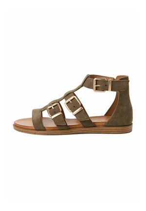 Sandale en daim vert olive avec trois larges brides et boucles couleur or. Semelle plate avec une texture de grain de bois naturel. Conception à talon ouvert.