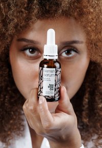 Blemish serum i en 30ml amber glassflaske med en hvit pipette. Har en svart-hvitt etikett med blomsterdesign og tekst.