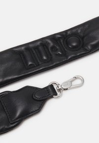 Zwarte leren schouderriem met reliëf-logo, voorzien van een zilveren metalen haak en een gevoerde textuur voor extra comfort.