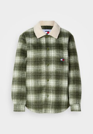 Chemise à carreaux verts et blancs avec un col en sherpa, dotée de boutons sur le devant et d'une poche poitrine avec une écusson logo. Texture du tissu douce.