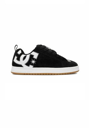 Czarny niski sneaker z białą podeszwą, brązowym bieżnikiem, czarnymi sznurówkami i dużym białym logo DC po boku.