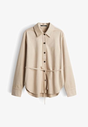 Camicia beige a maniche lunghe con bottoni, collo appuntito e sottile cintura in vita, realizzata in tessuto liscio, mostrata distesa su sfondo bianco.