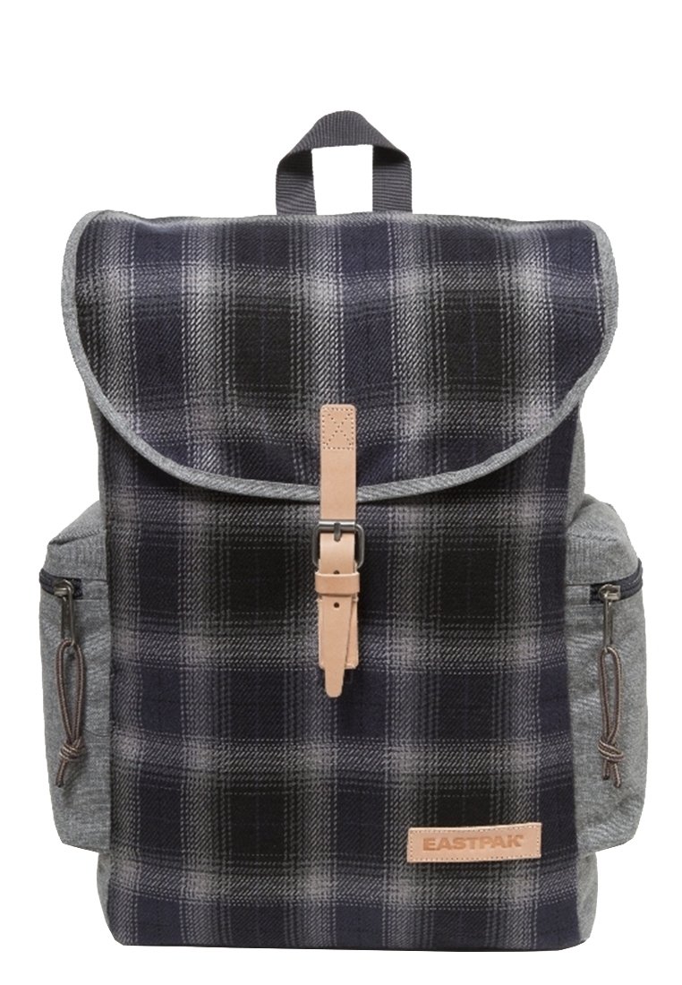 Ryggsäck med marinblå och grå rutigt tyg, grå sidofickor, läderremmar och ett viklock med spänne.