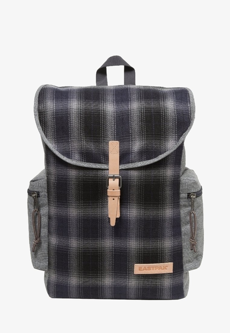 Reppu, jossa on laivastonsinistä ja harmaata ruutukangasta, harmaat sivutaskut, nahkanyöriasusteet ja taitettava läppä, jossa on solkilukko.