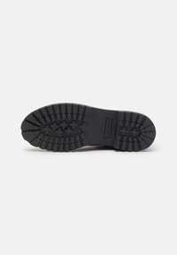 Suela de bota de goma negra con un patrón de banda de rodadura resistente. Presenta líneas estriadas y acentos circulares para tracción y durabilidad. Perfil plano.