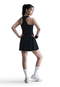 Black athletic dress with a flared skirt, sleeveless design, paired with white knee-high socks and white Nike athletic shoes.