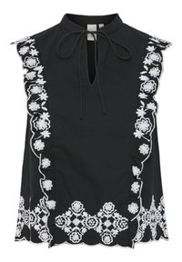 Haut noir sans manches avec broderie florale blanche le long de l'encolure et de l'ourlet, avec une ouverture en forme de goutte et un détail à nouer au niveau du cou.