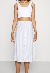 White cropped tank top with a round neckline paired with a mid-length light blue and white striped skirt featuring front buttons.