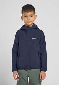 Navy blue softshell jacket with a hood, two zippered side pockets, and a logo on the chest, made from a lightweight, water-resistant material.