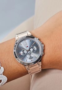 Reloj cronógrafo en tono plateado con una esfera azul-gris, acentos en oro rosa, tres subesferas y una pulsera de eslabones metálicos. Presenta tres coronas.