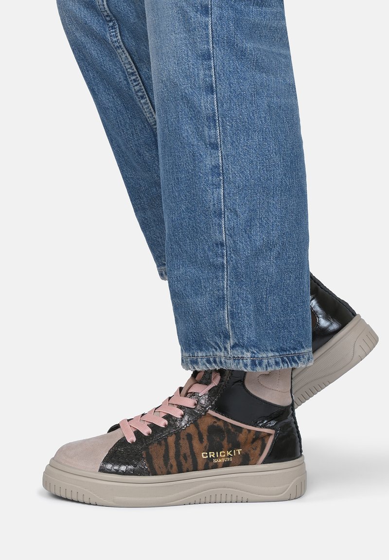 Sneakers typu high-top z połączenia gładkiego czarnego materiału, tkaniny w zwierzęcy wzór, jasnoróżowych sznurówek oraz beżowej podeszwy z teksturowanymi akcentami.