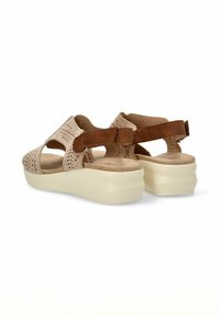 Sandalias beige con parte superior perforada, correas de acento marrón y una suela gruesa blanca. Diseño abierto para transpirabilidad y comodidad.
