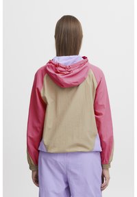 Chaqueta cortaviento con bloques de color que presenta un diseño en rosa y beige, fabricada en un tejido ligero, con puños elásticos y capucha con cordón.