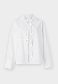 White long-sleeve shirt made of smooth fabric features a button-down collar, front tie closure, and cuffed sleeves. Simple and clean design.