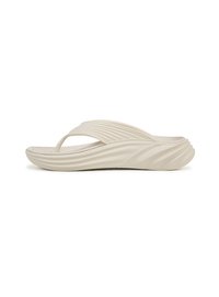 Sandale flip-flop beige avec un motif en vague texturé sur la lanière et la semelle, présentant une finition lisse et une forme minimaliste.