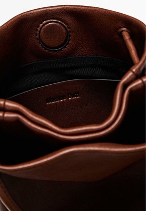 Inuti en brun läderväska med mjuk struktur, med svart foder och ett cirkulärt lås. Pr präglad "Massimo Dutti"-logotyp synlig.