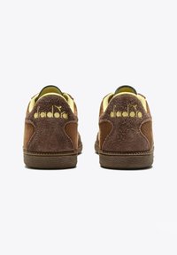 Sneaker in suede marrone con dettagli gialli, dotate di suola testurizzata e logo "diadora" sul tallone. Design a profilo basso.