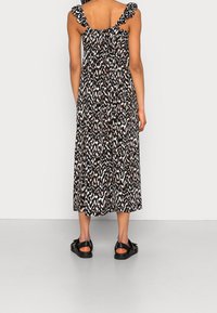 Maxi šaty s černobílým vzorem, volánkovými ramínky, splývavou sukní a měkkou texturou látky. V páru s černými sandály.