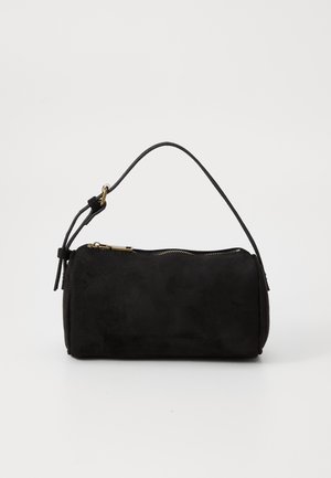 Petit sac à main cylindrique en daim noir avec une fine bandoulière unique et une fermeture éclair dorée sur le dessus, sur fond uni.