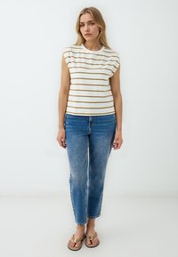Top corto a righe crema con maniche corte abbinato a jeans blu a vita alta e sandali marroni, caratterizzato da una vestibilità rilassata e un design informale.