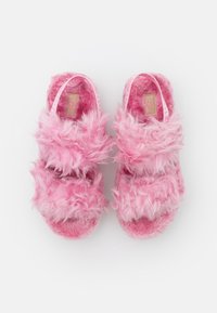 Futrzaste różowe klapki z dwoma szerokimi paskami, teksturowany materiał, miękka podszewka wewnętrzna oraz wyściełana wkładka. Widoczna logo UGG.