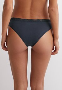 Culotte en coton bleu marine avec une bordure en dentelle à la taille. Le design présente une texture lisse et une coupe classique taille moyenne.