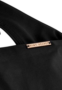 Črna usnjena torbica z gladko teksturo. Ima pravokotni kovinski oznako z vgraviranim napisom "MINT VELVET" v moderni pisavi.