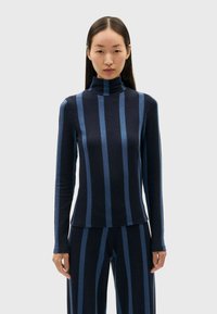 Navy turtleneck top met donkerblauwe verticale strepen, lange mouwen, aansluitend ontwerp en zachte textuur, gecombineerd met bijpassende gestreepte broek.