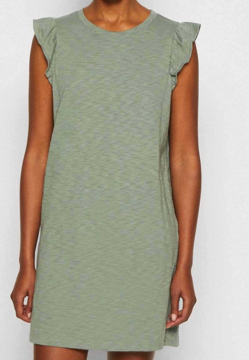 Robe courte verte à coupe décontractée, col rond et épaules à volants. Tissu doux et texturé avec un motif subtil.