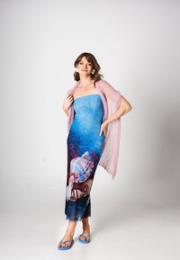 Beżowa sukienka bez ramiączek z muszlowym wzorem, koralowymi akcentami i przezroczystą warstwą materiału; w połączeniu z różowym szalem i niebieskimi sandałami.