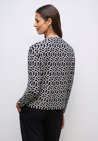 Zwart-witte, gemêleerde top met een geometrisch ontwerp, lange mouwen, ronde hals en zachte stof. Geschikt voor casual draag.