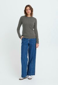Gray knitted sweater with a cable pattern, paired with wide-leg denim jeans and white sneakers, standing on a plain background.