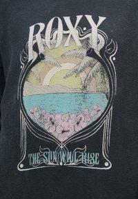 Czarna dzianina w gofrowany wzór z grafiką przedstawiającą palmy, turkusowe morze, różowe kwiaty oraz tekst "ROXY THE SUN WILL RISE".