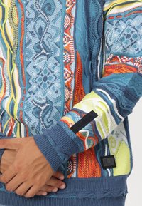 Gebreide pullover met een multicolor patroon in blauw, oranje, geel en groen. Geribbelde manchetten en zoom, logo patches aanwezig.