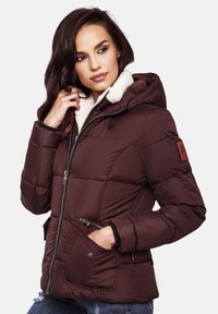 Burgundy puffer jacket with a hood, zip closure, faux fur collar, and side pockets; features quilted pattern and branded patch on sleeve.