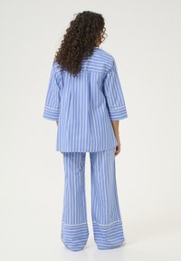 Completo due pezzi a righe blu e bianche, composto da una maglia a maniche lunghe e vestibilità ampia e pantaloni a gamba larga con dettaglio di orlo bianco solido.