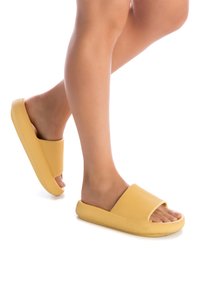 Chanclas de goma amarillas con un acabado texturizado, diseño de punta abierta y una banda ancha, que cuentan con una suela gruesa para mayor comodidad y agarre.